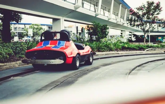 featured-image-1749560468 | Hot Party Stripper A red car driving down a track in front of a building.