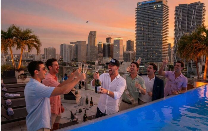 Best man and groom celebrating a Miami bachelor party on a luxury rooftop with skyline view at sunset